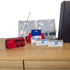 Udpakket PrepBox Essentials med nødradio, førstehjælpssæt, nødtæpper, vandrensningstabletter og sort opbevaringsæske.