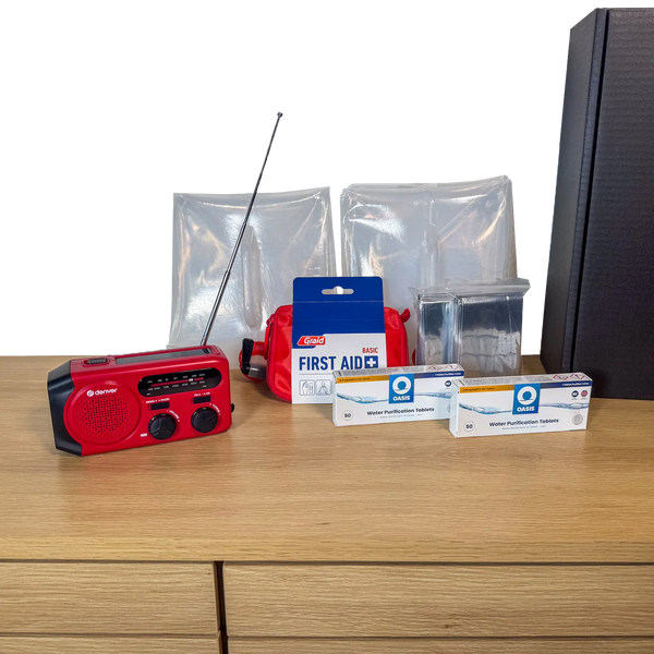 Udpakket PrepBox Essentials med nødradio, førstehjælpssæt, nødtæpper, vandrensningstabletter og sort opbevaringsæske.