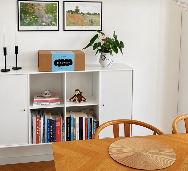 PrepBox til én person placeret på en reol i en stue med bøger, planter og billeder på væggen.